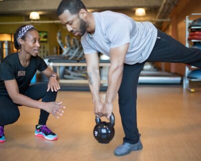 man with kettlebell working with personal trainer at Boulder Athletic Club