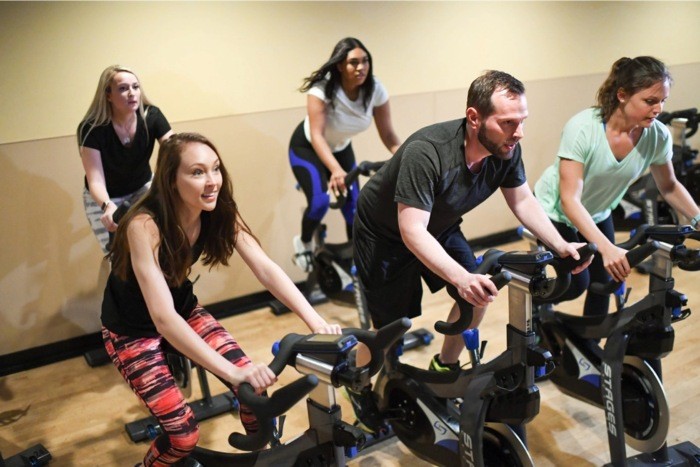 A Group of People Cycling on Stationary Bikes in a Fitness Center in CO
