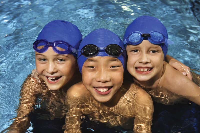 Children in swim class wearing blue caps at Sports & Wellness Highpoint at Wellbridge
