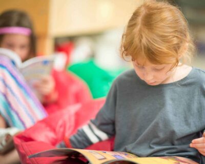 A young girl sitting on a bean bag engrossed in reading a book in Albuquerque, NM