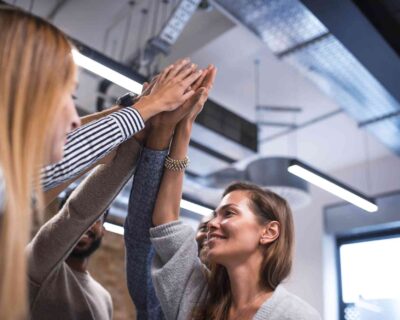Five colleagues in an office giving high fives celebrating Fitness Events in Albuquerque, NM