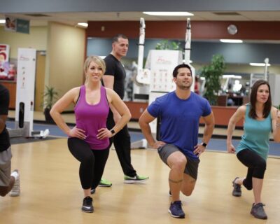 A group of individuals performing squats in a gym setting, part of training programs at Wellbridge