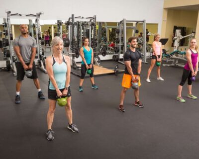 A group of people exercising in a gym using kettlebells, training programs at Wellbridge