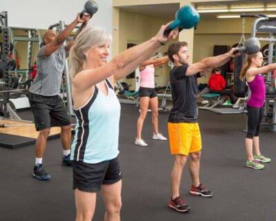 A group of people in a gym holding kettlebells and engaging in a workout session in Albuquerque, NM