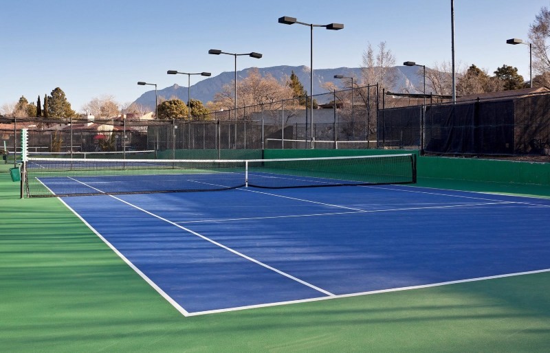 Tennis player hitting a forehand shot on outdoor court at Wellbridge