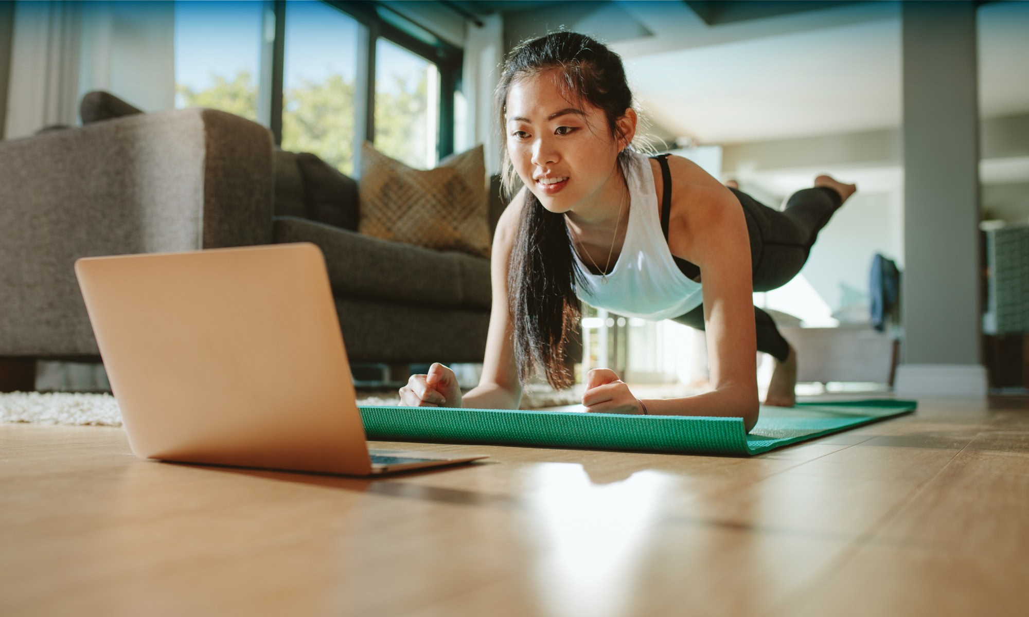a girl excising while watching videos in laptop in home