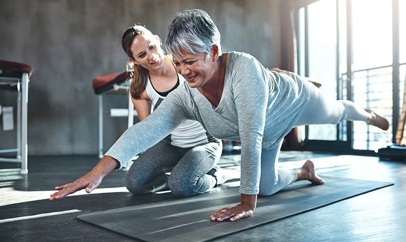 Old women doing exercise with help of trainer, CO
