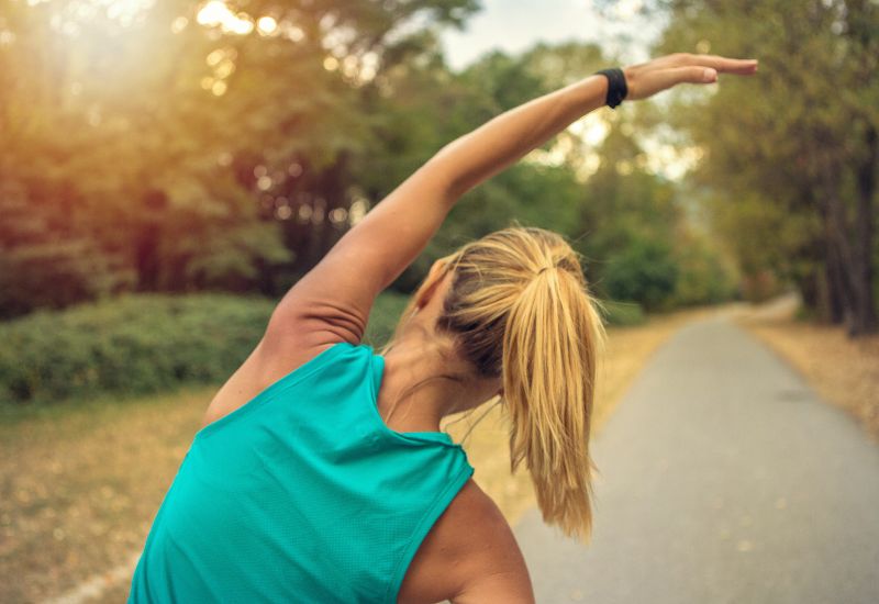 A woman stretching pre-run to work out at a Wellbridge Athletic Club.